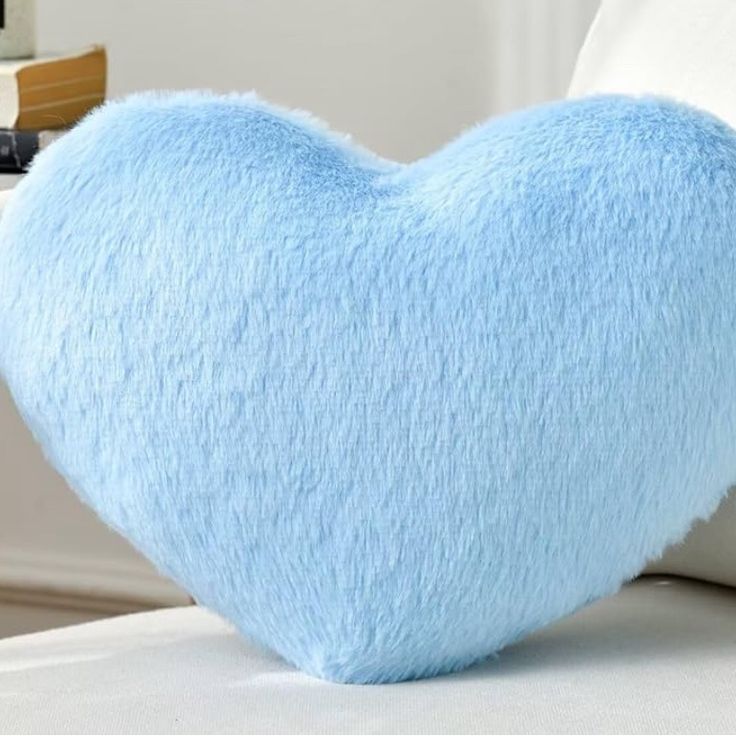 a blue heart shaped pillow sitting on top of a bed