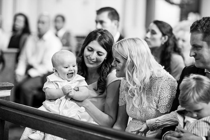 a group of people sitting next to each other in front of a wooden bench holding a baby