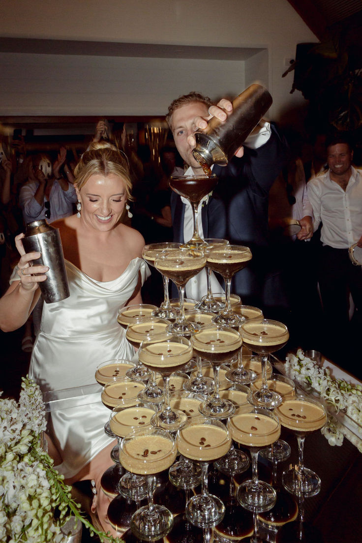 a bride and groom standing behind a table filled with champagne