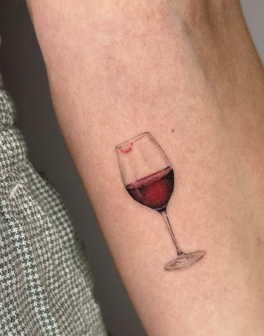 a woman's arm with a glass of red wine on the left side of her arm