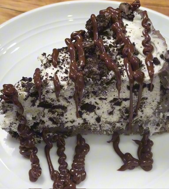 a piece of cake on a plate with chocolate drizzles and whipped cream