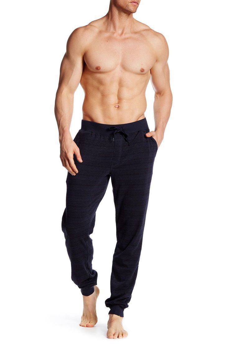 a shirtless man with no shirt standing in front of a white background wearing black sweatpants