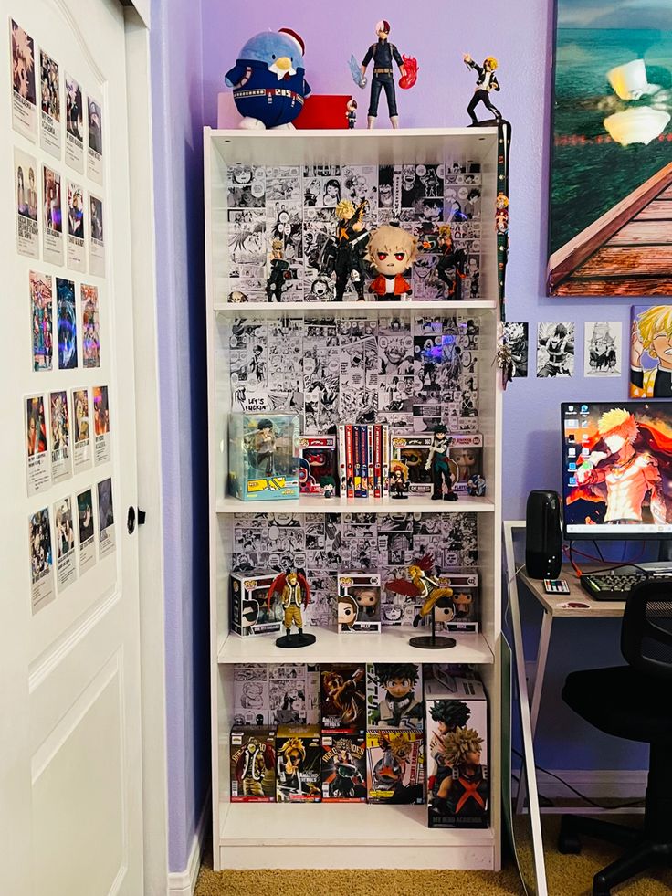 a book shelf filled with comic books next to a computer desk and wall mounted pictures