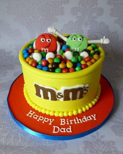 a birthday cake decorated with candy and candies in a yellow bowl on top of a red plate