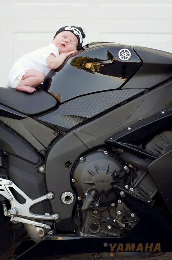 a baby laying on top of a black motorcycle