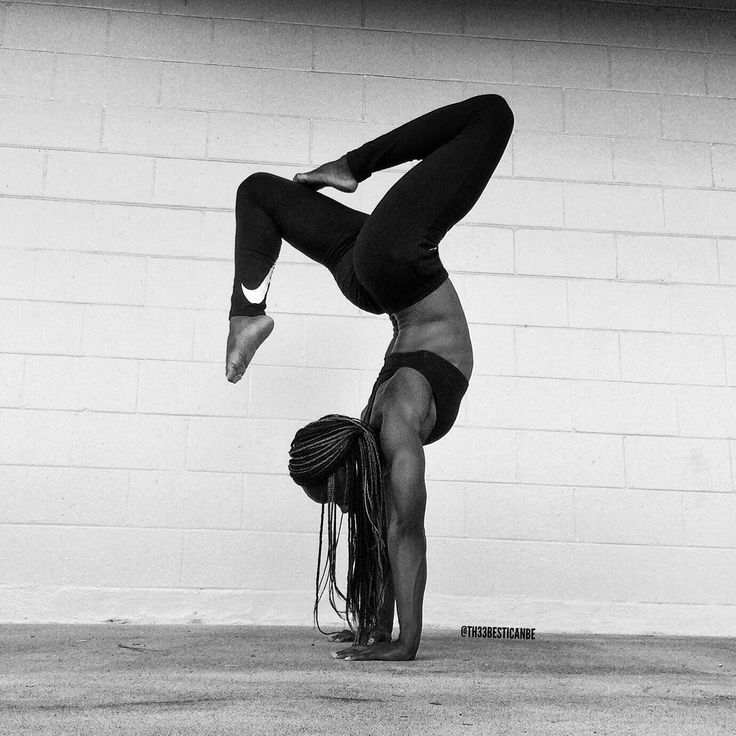 a woman doing a handstand in front of a brick wall with her legs spread out