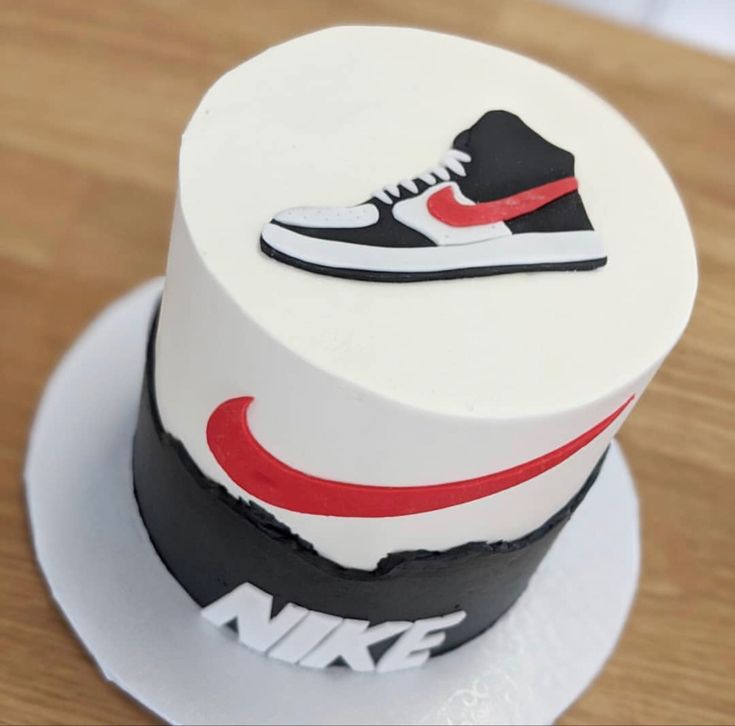 a white cake with red and black nike shoes on it's top, sitting on a plate