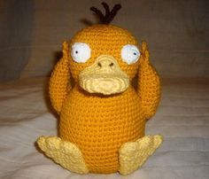 a crocheted yellow bird sitting on top of a bed