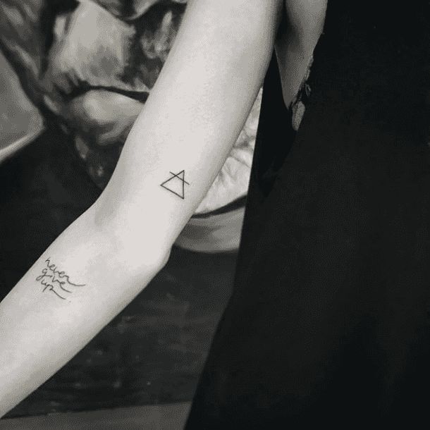 a person with a tattoo on their arm holding something in one hand and an object in the other