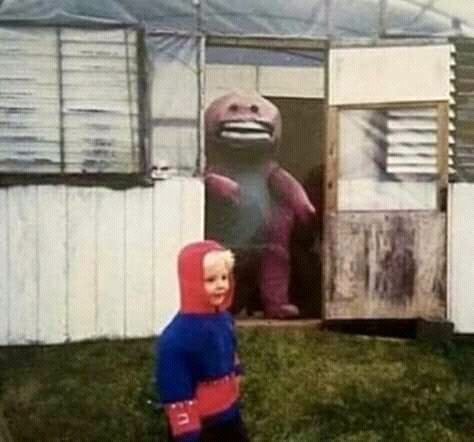 a little boy standing in front of a giant stuffed animal and wearing a red hoodie