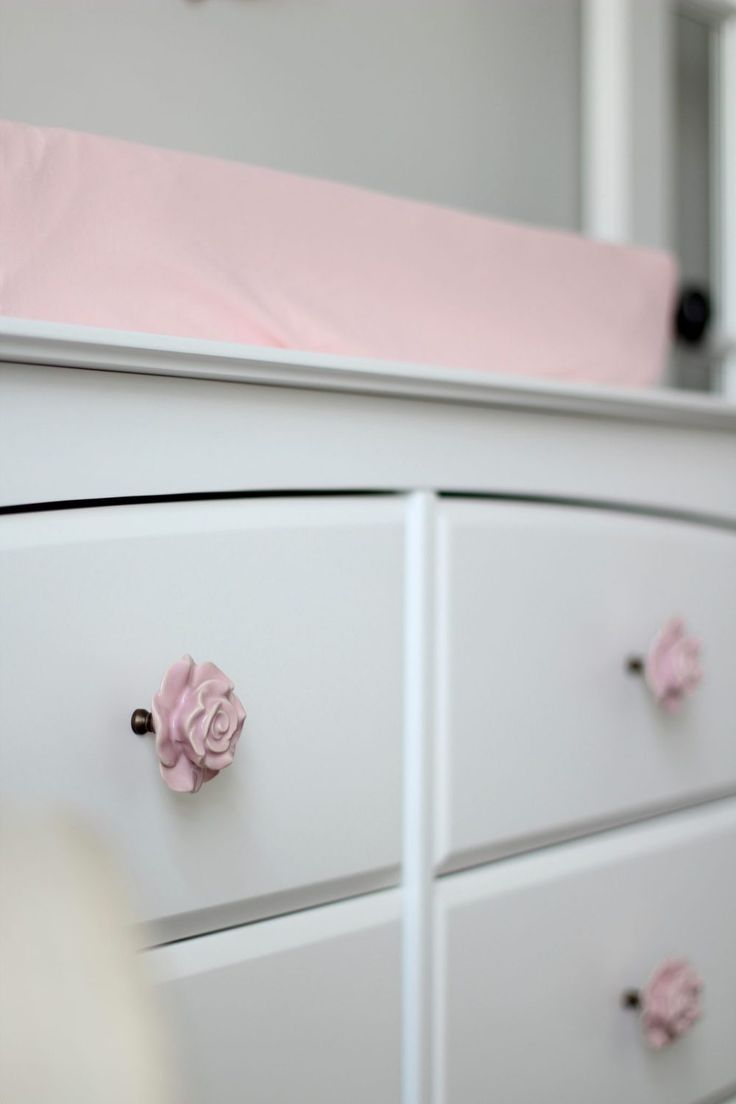 a white dresser with pink flowers on the drawers