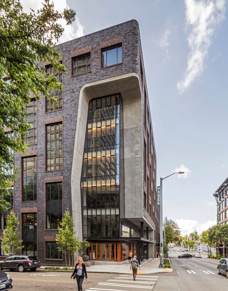 an unusual building on the corner of a street with people walking around in front of it