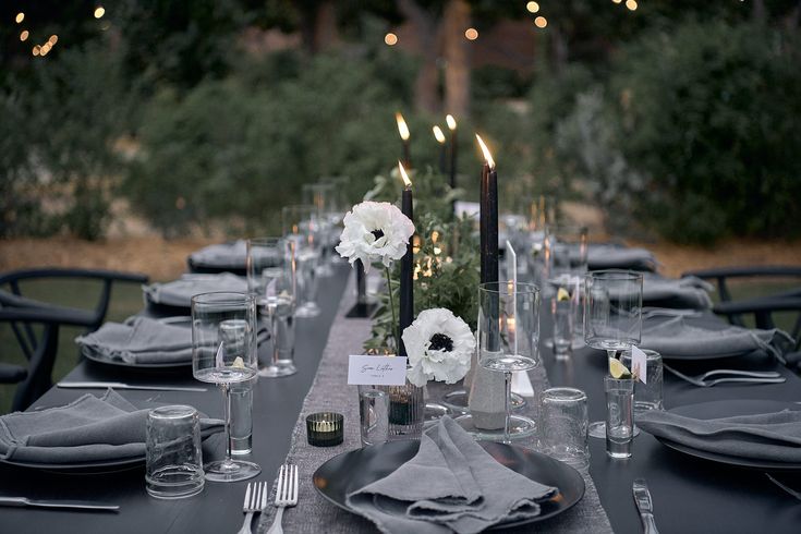 the table is set with candles, plates and napkins for an elegant dinner party