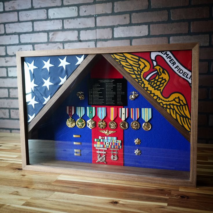 a shadow box with medals and an american flag in the bottom right corner on a wooden table