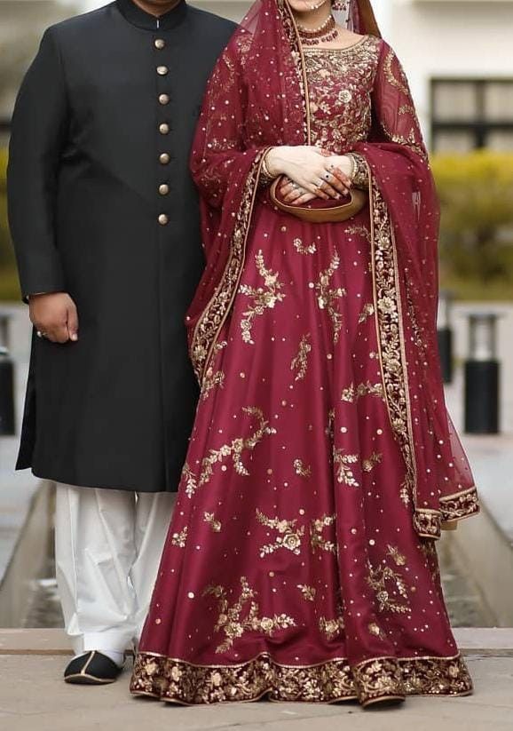 two people standing next to each other in formal wear, one wearing a red and gold outfit