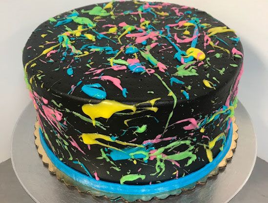 a black cake with multicolored splatters on the icing and frosting