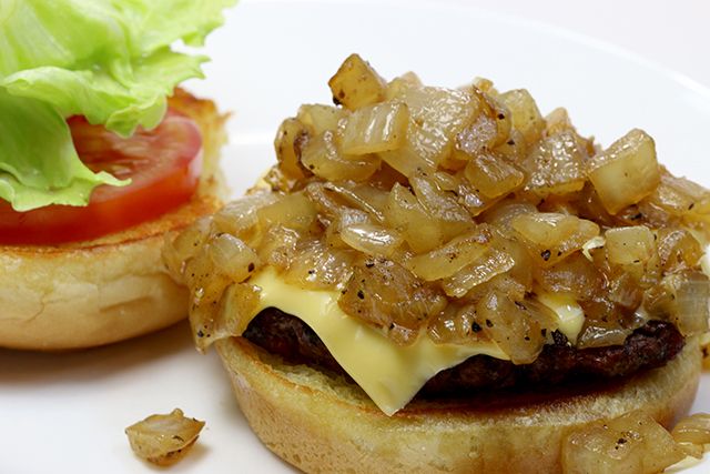 a hamburger with onions and lettuce is on a plate next to a tomato