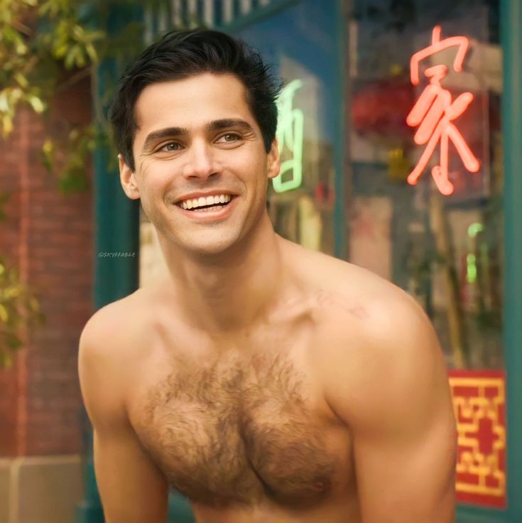 a shirtless man with no shirt standing in front of a neon sign and smiling at the camera