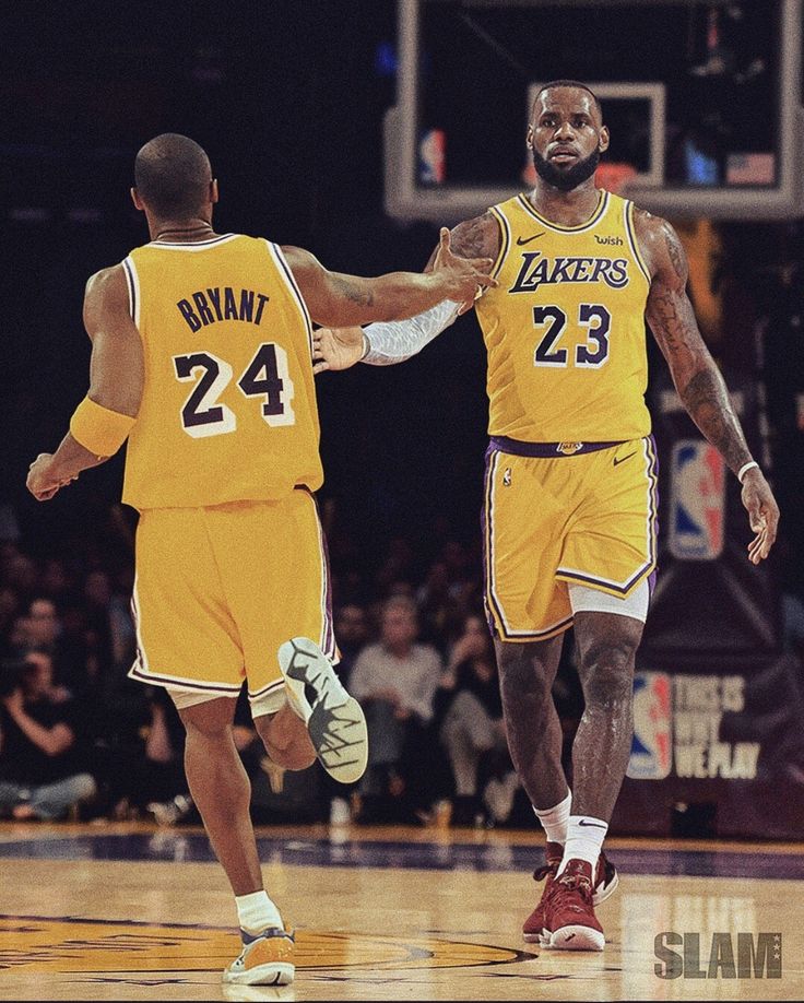 two basketball players in yellow uniforms are shaking hands on the court while an audience looks on