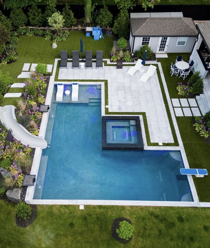 an aerial view of a backyard with a swimming pool and lounge chairs on the lawn