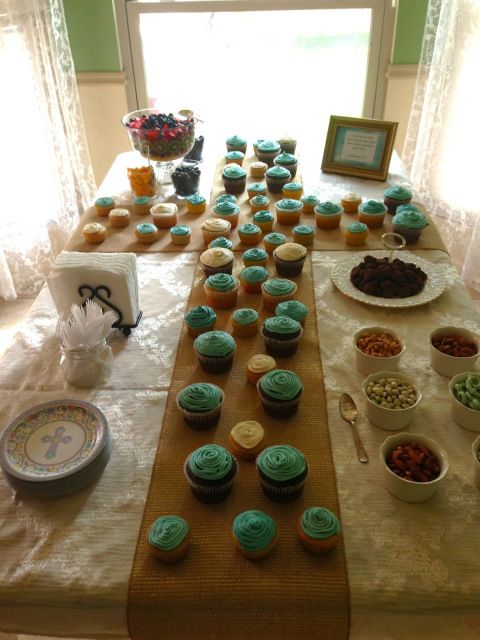 a table topped with lots of cupcakes covered in frosting