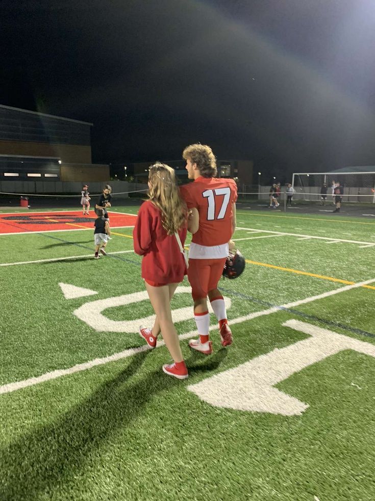 two people standing on a football field at night