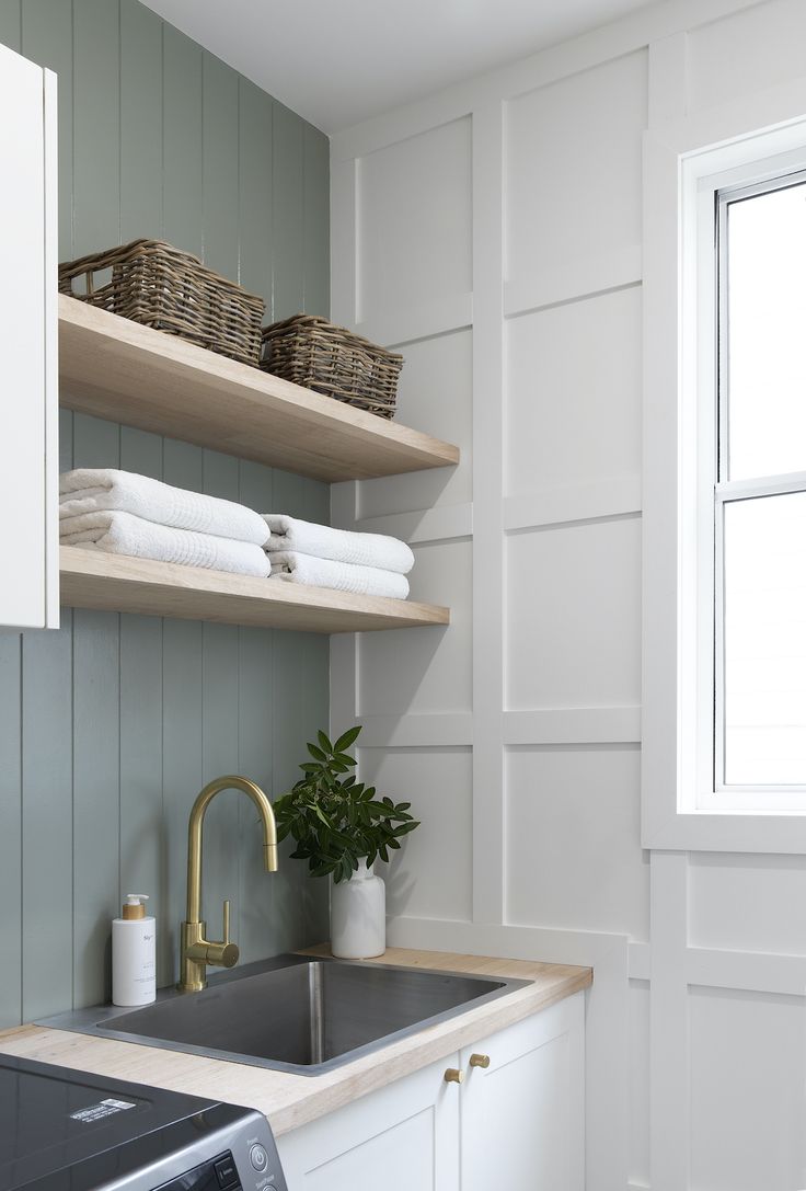 a washer and dryer in a small room with open shelving on the wall