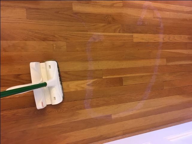 a green and white toothbrush sitting on top of a wooden floor next to a wall