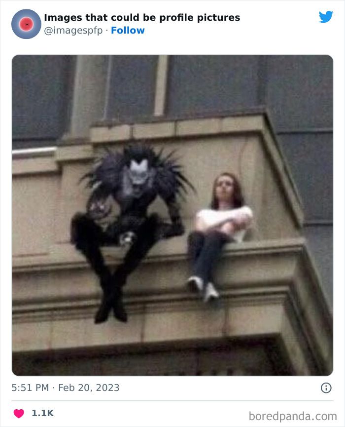 a woman sitting on top of a building next to a giant spider man