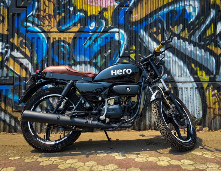 a motorcycle parked in front of a wall with graffiti on it's sides and back