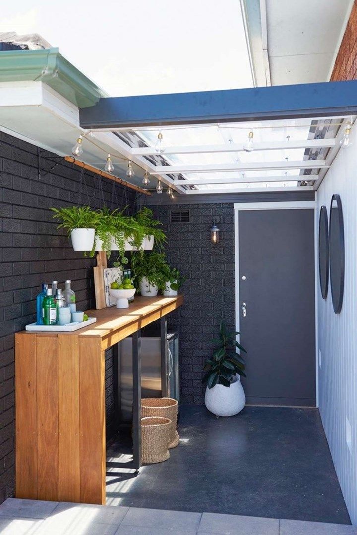 an outdoor room with plants on the counter and potted plants on the shelf next to the door