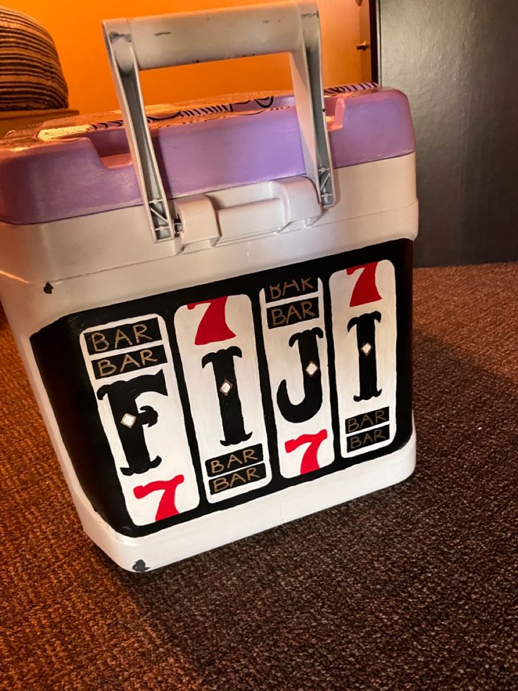 a white and purple lunch box sitting on top of a brown carpeted floor next to an orange wall