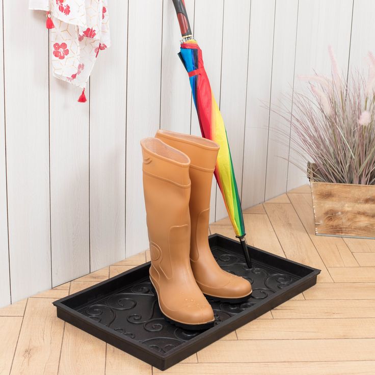 a pair of rubber boots and an umbrella on a mat