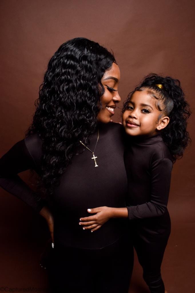 a pregnant woman and her child are posing for a photo in front of a brown background