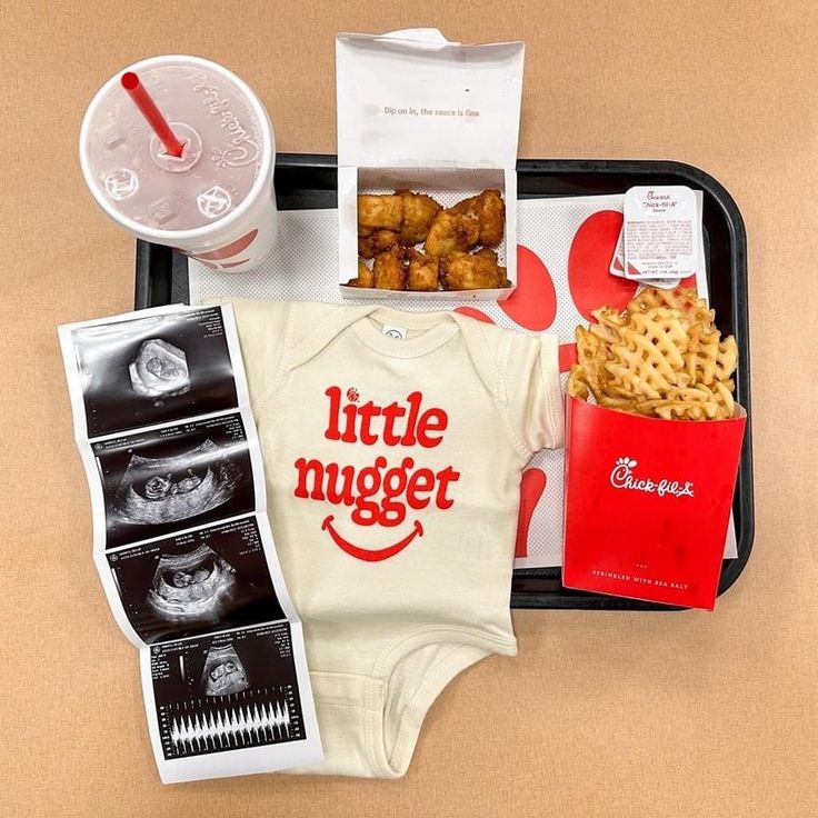 a tray that has some food and drinks on it, including an infant's bodysuit