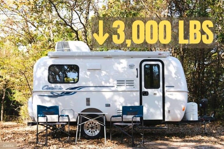 an rv parked in the woods next to a table with chairs and a sign that says 3, 000lbs