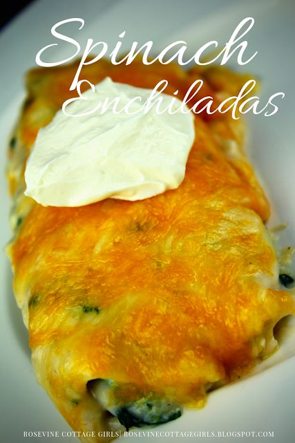 spinach enchiladas on a white plate with sour cream in the middle