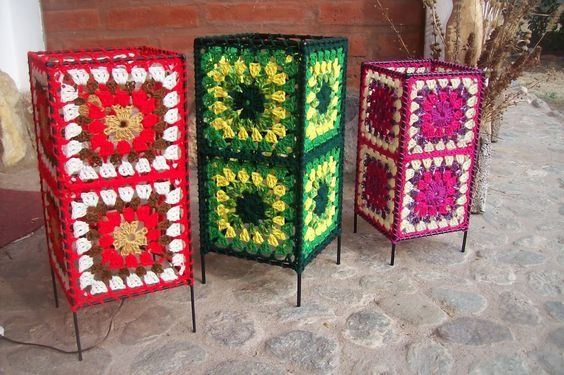 four different colored crocheted boxes sitting next to each other on top of a stone floor