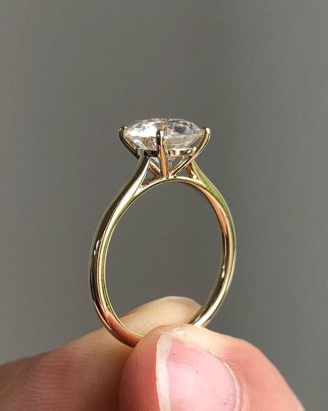 a close up of a person's hand holding a ring with a diamond on it