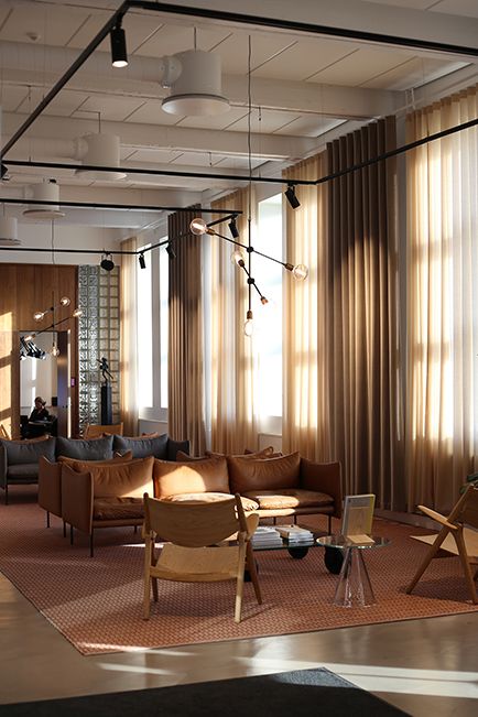 a living room filled with lots of furniture next to tall windows covered in light curtains