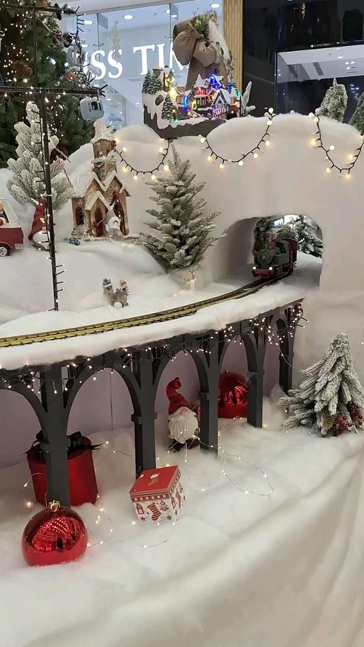 a toy train set is on display in the snow with christmas trees and lights around it