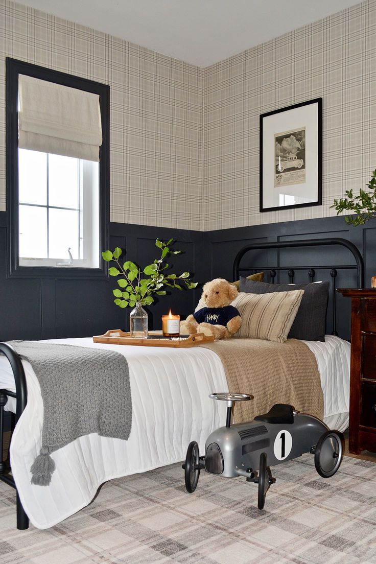 a teddy bear sitting on top of a bed next to a dresser and window in a bedroom