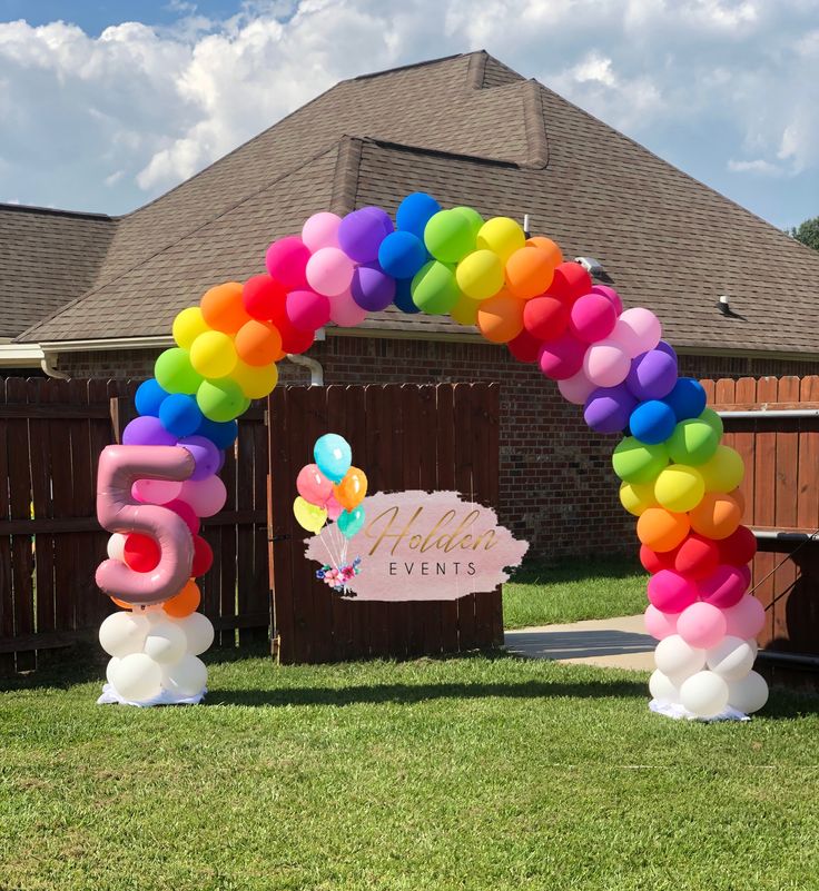 an arch made out of balloons with the number five on it in front of a house