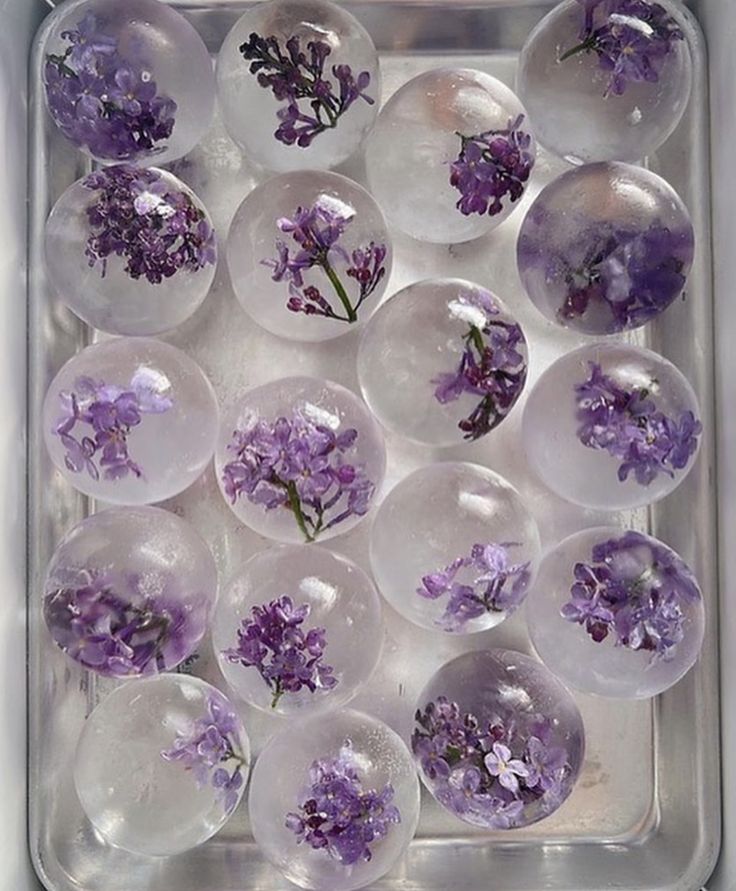 purple flowers are placed in clear glass balls