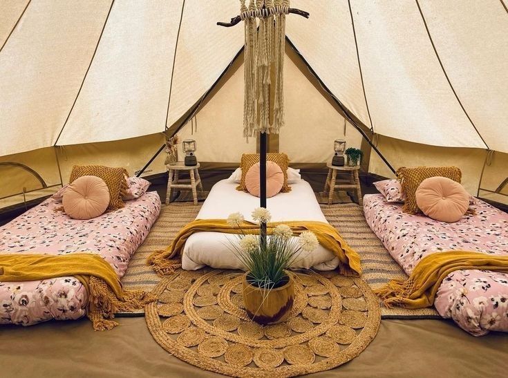 the inside of a tent with three beds and an umbrella