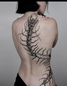 the back of a woman's body with tattoos on it