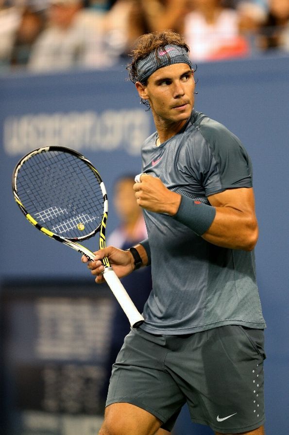 a man holding a tennis racquet on top of a tennis court with people in the background