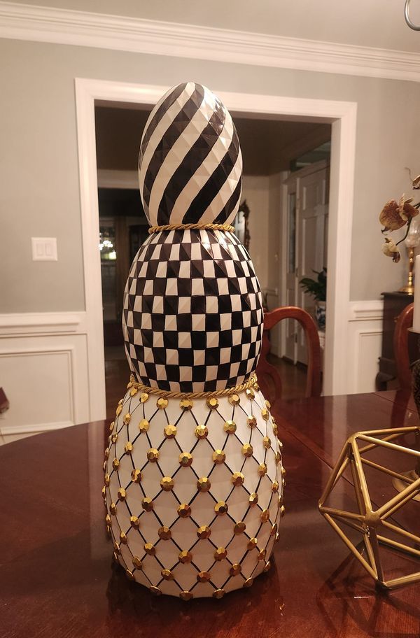 a large black and white vase sitting on top of a wooden table