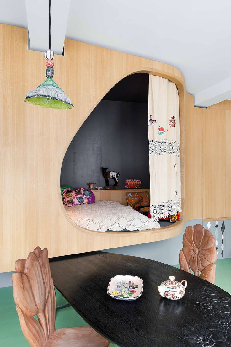 a room with a table, chairs and a mirror on the wall above it that is shaped like an oval window