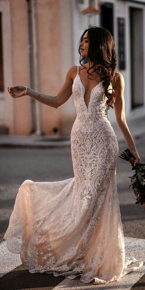 a woman in a wedding dress is walking down the street with her hand out and holding flowers